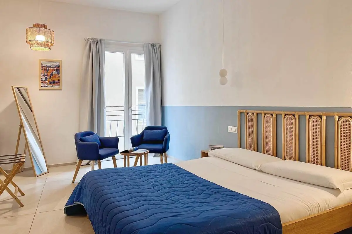 Letto matrimoniale e salottino accanto alla portafinestra